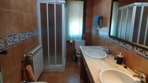A bathroom with two sinks, a shower, and a toilet.