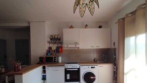 A compact kitchen with a washing machine, microwave, and stove.