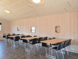 Un salón de conferencias con varias mesas y sillas, paredes de paneles de madera y piso de baldosas de piedra.