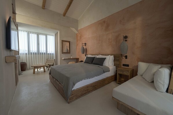 A bedroom with a large bed, a smaller bed, a TV, a desk, and a chair. - Wakana Alaçatı (Cesme)