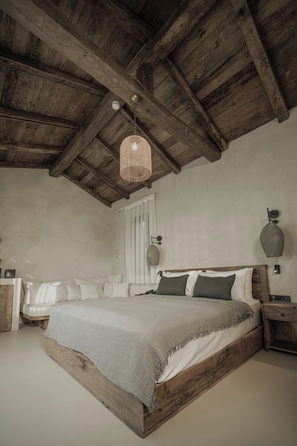 A bedroom with a wooden bed frame, a hanging light fixture, and a nightstand with a lamp. - Wakana Alaçatı (Cesme)
