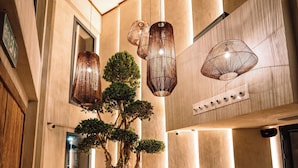 Un hallo espacioso con un gran bonsái, muebles de mimbre e iluminación colgante moderna.