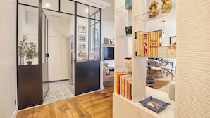 Un intérieur moderne avec un plancher en bois, une cloison en verre et une bibliothèque contenant des livres et des objets décoratifs.