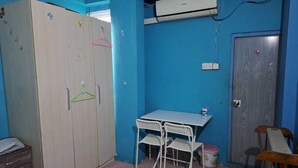 A room with a wardrobe, a table with chairs, an air conditioner, and a door.