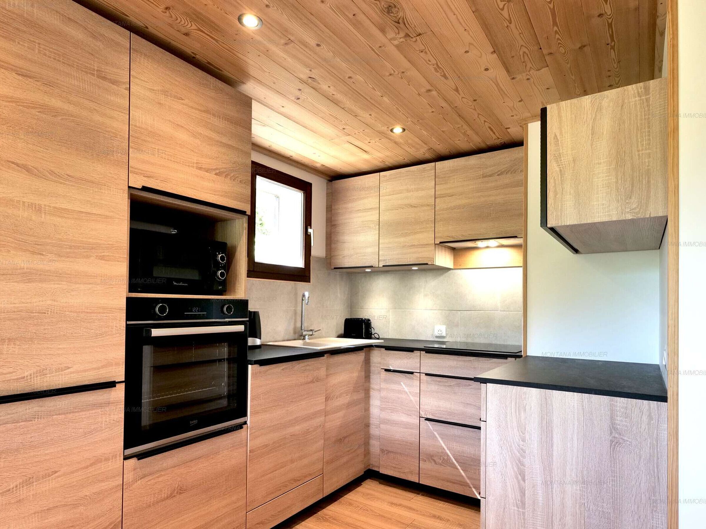 A modern kitchen with wooden cabinetry, a built-in oven, and a microwave.