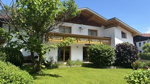 A two-story house with a sloped roof, a balcony, and a well-maintained garden. - Nice apartment for 6 people with WIFI, TV, terrace and pets allowed (Reutte)