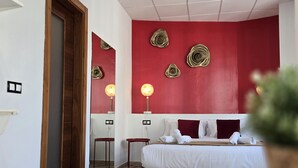 A hotel room with a bed, bedside tables, and a red accent wall with decorative elements. - Design suites in central Malaga, near museums and Calle Larios (Málaga)