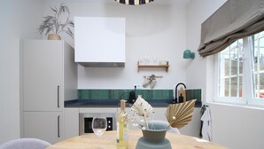 A modern kitchen with white cabinets, a wooden table, a wine glass, a bottle, and decorative items.