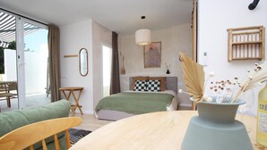 A modern bedroom with a bed, a wooden table, a chair, and a large window.