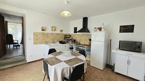 Una cocina compacta con comedor, un refrigerador blanco, un microondas y un televisor pequeño sobre un mueble.
