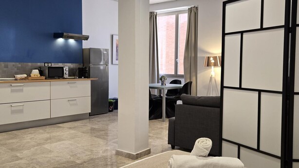 A modern hotel room with a kitchenette, a dining area, and a seating space. - Design Suites in Malaga Center - Comfortable Accommodation (Málaga)
