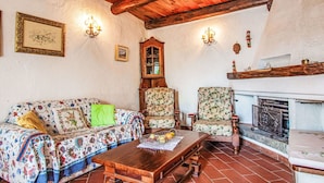 Un soggiorno rustico con soffitto in legno, un divano floreale, un tavolo in legno e un camino.