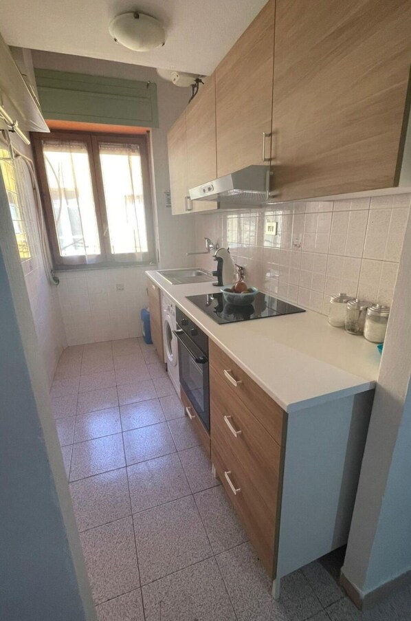 Una cocina compacta con horno integrado, un lavamanos y una ventana.