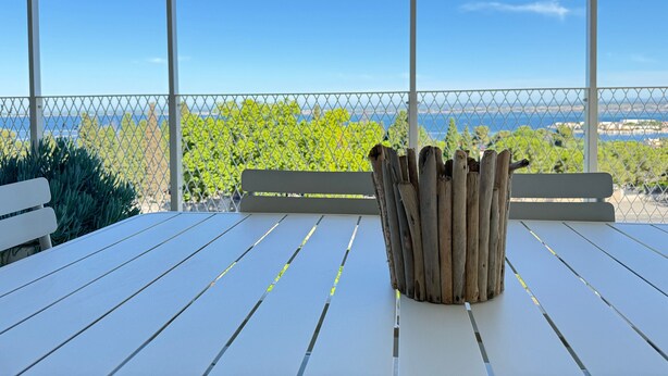 A white wooden table with a rustic wooden planter in the center, set against a backdrop of a clear blue sky and a distant view of a coastline. - Elegant T2 with terrace in Sète, secure parking (Sète)