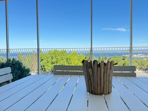 A white wooden table with a rustic wooden planter in the center, set against a backdrop of a clear blue sky and a distant view of a coastline. - Elegant T2 with terrace in Sète, secure parking (Sète)