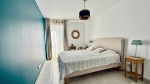 A bedroom with a bed, a bedside table, a lamp, a wall clock, and a window with curtains. - Elegant T2 with terrace in Sète, secure parking (Sète)