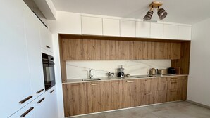 A modern kitchen with white cabinets, a wooden countertop, and a marble backsplash. - Elegant T2 with terrace in Sète, secure parking (Sète)