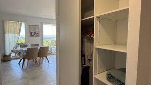 A room with a dining area, a view through a window, and a closet with shelves. - Elegant T2 with terrace in Sète, secure parking (Sète)