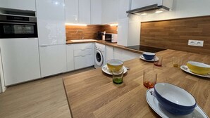 A modern kitchen with white cabinets, a wooden countertop, a built-in washing machine, and a microwave.