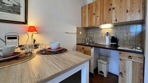 Une cuisine compacte avec des meubles en bois, un petit évier et une machine à café.