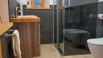 A modern bathroom with a glass-enclosed shower, a wooden vanity, and a white toilet.