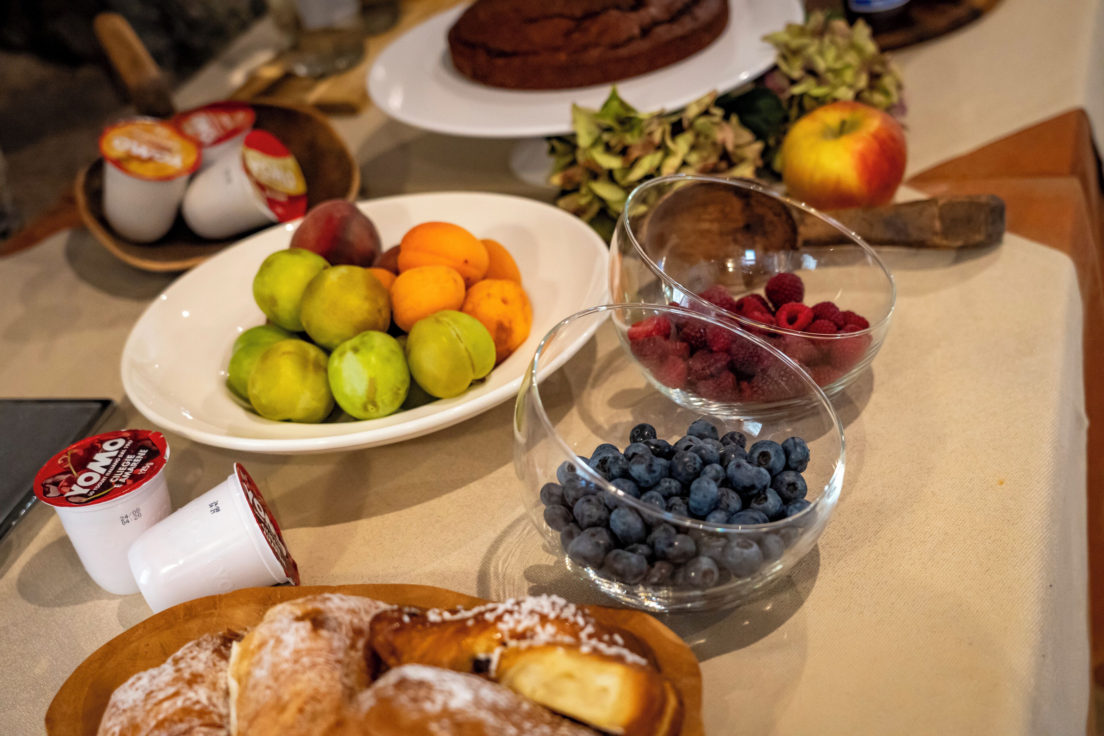 A table with various food items including fruits, pastries, and a plate of cookies.