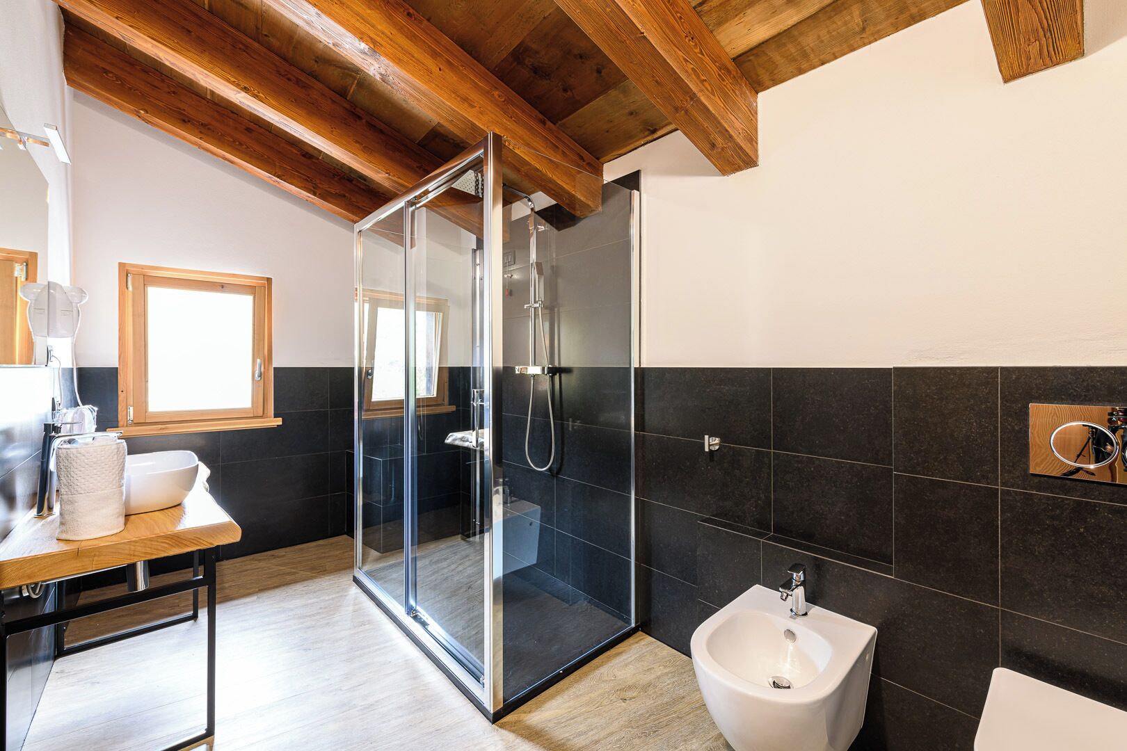 A modern bathroom with a glass shower enclosure, a bidet, and a wooden vanity with a sink.