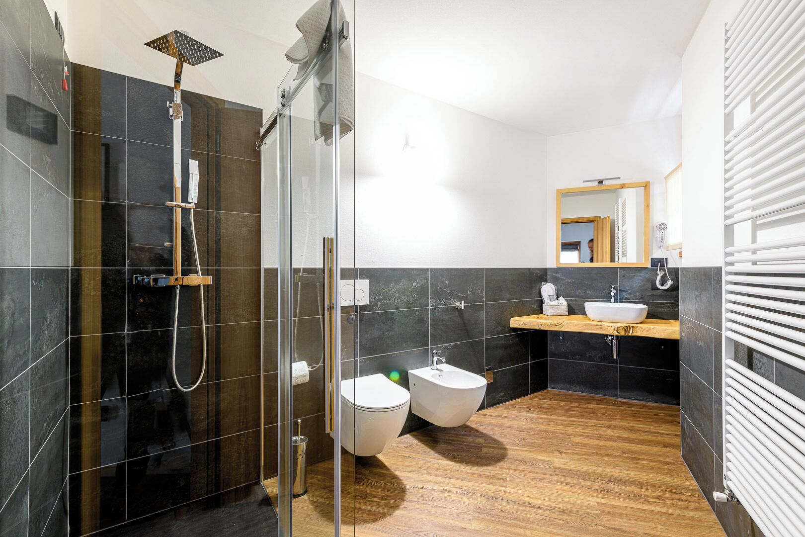 A modern bathroom with a glass-enclosed shower, a wooden vanity with a sink, and a toilet.
