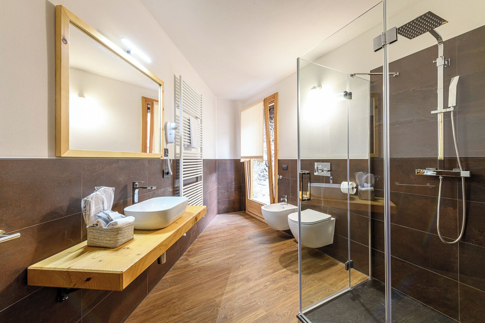A modern bathroom with a large mirror, two sinks, a shower, and a wooden vanity.
