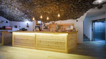 A rustic interior with a stone ceiling, wooden counter, and hanging light fixtures.