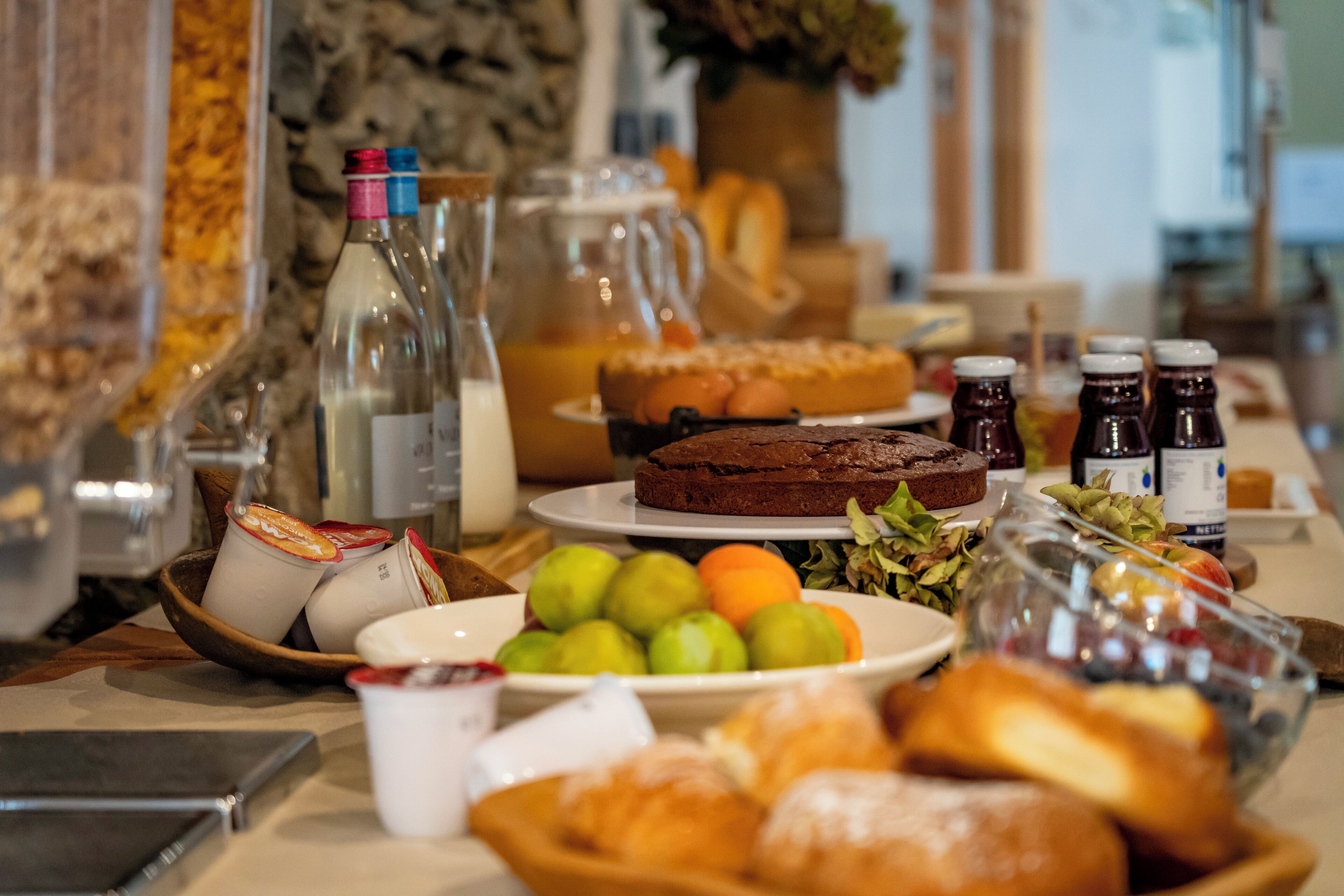A buffet table with various food items, including pastries, fruits, and beverages.