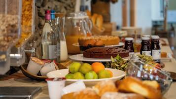 A buffet table with various food items, including pastries, fruits, and beverages.