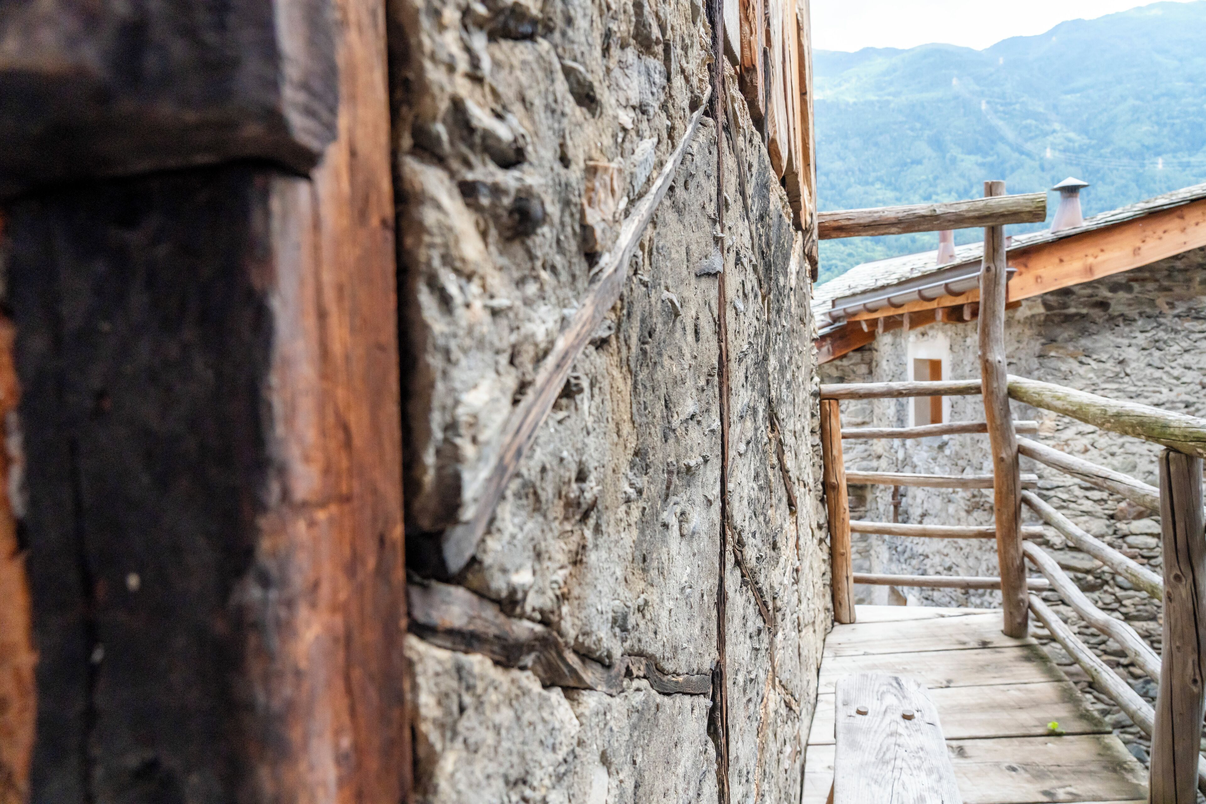 A wooden staircase leading up to a stone building with a wooden railing.