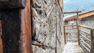 A wooden staircase leading up to a stone building with a wooden railing.