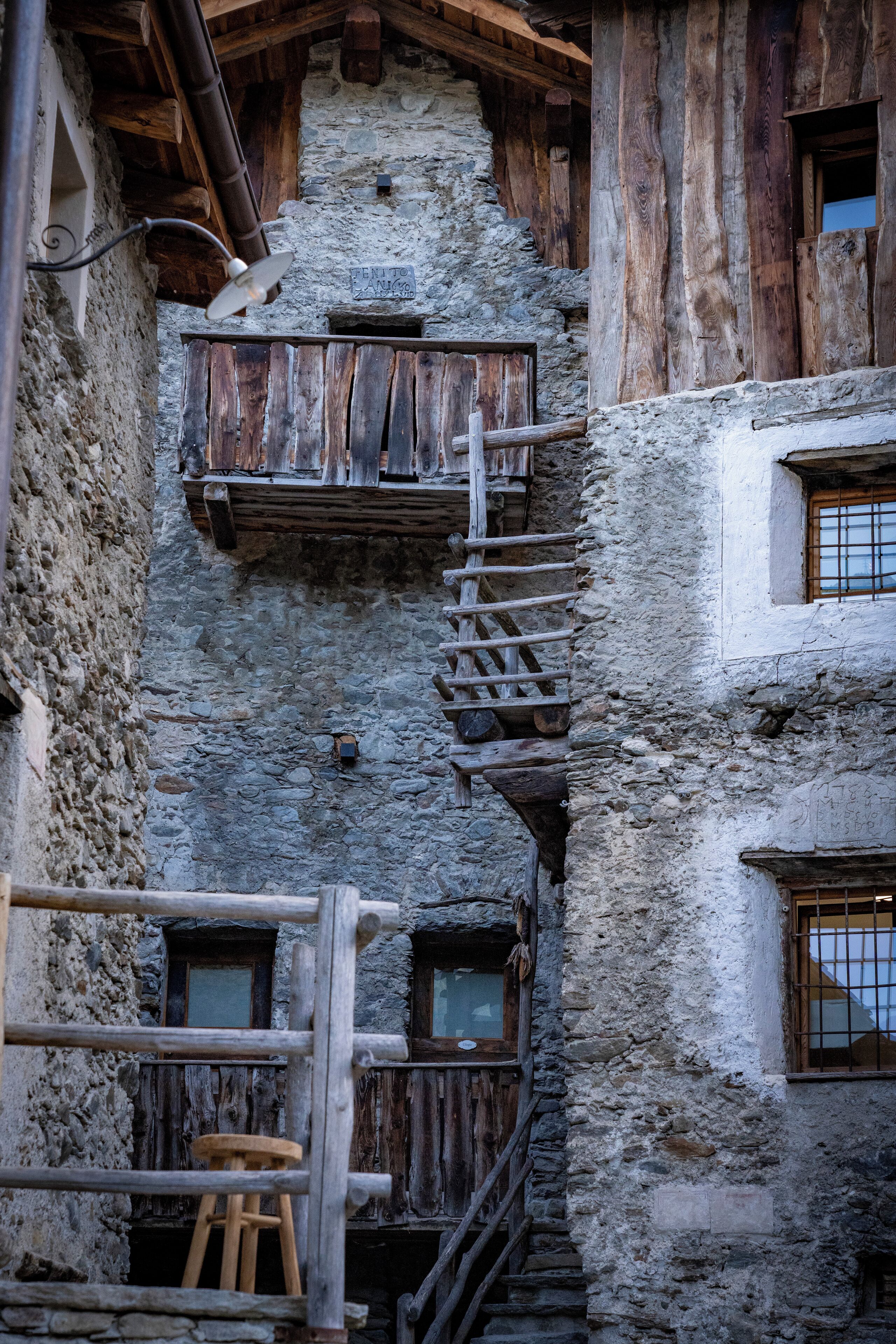 Un edificio rustico in pietra con balconi in legno e una scala in legno.