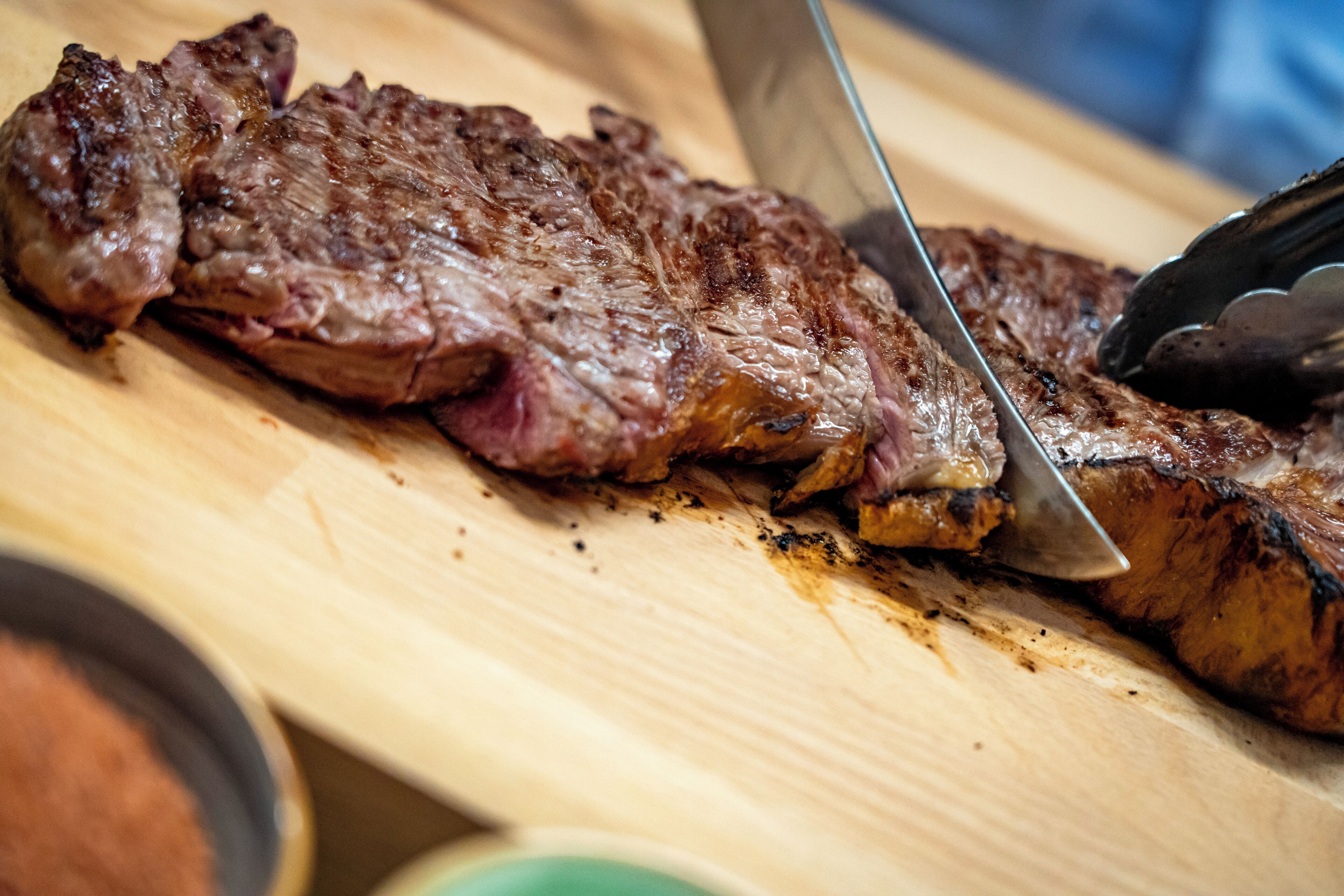 A steak being sliced on a wooden cutting board.
