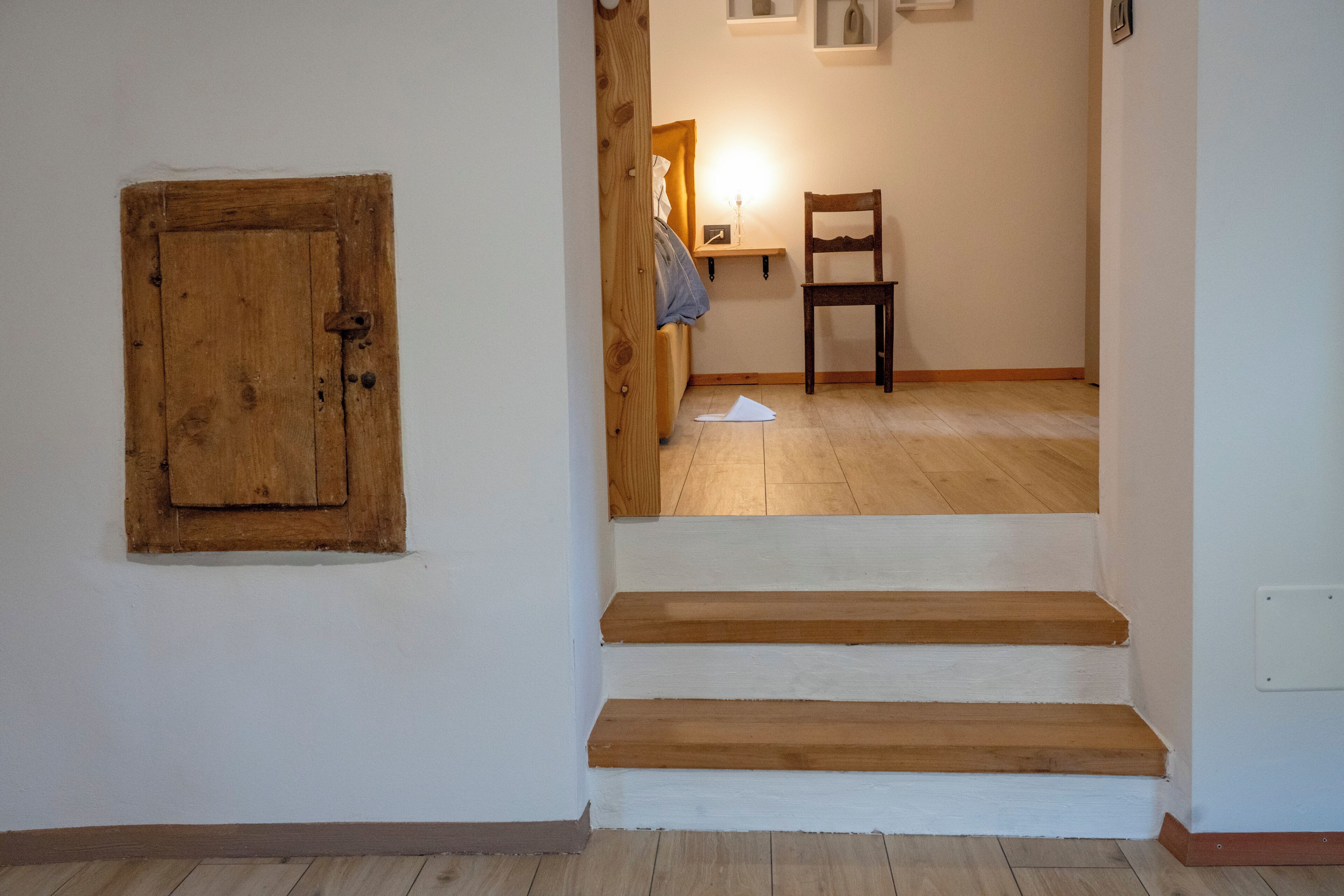 Een trap die leidt naar een slaapkamer met een houten deur en een stoel.