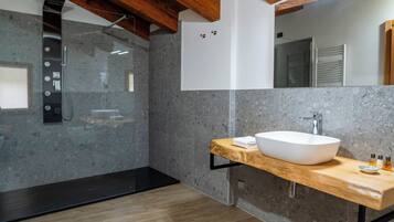 Een moderne badkamer met een vrijstaand bad, een grote spiegel en een houten wastafelmeubel met een waskom.