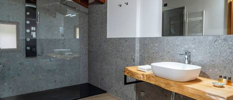 A modern bathroom with a freestanding bathtub, a large mirror, and a wooden vanity with a vessel sink.