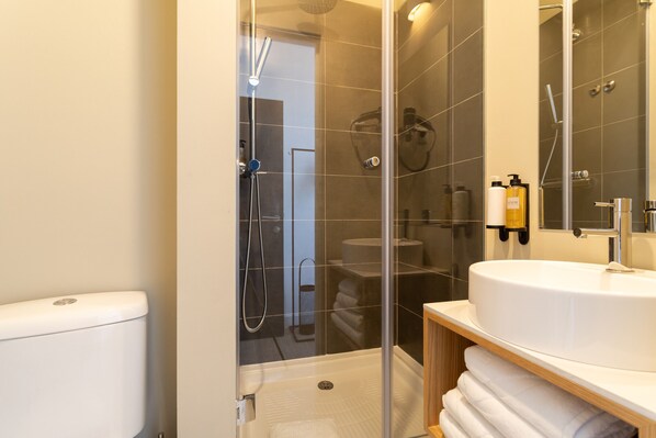 A modern bathroom with a glass-enclosed shower, a white sink, and a wooden vanity. - Lapa Diplomatic Suite 2.2 by Feel Lisboa (Lisboa ciudad)
