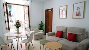 Un salon avec un canapé, deux fauteuils, une table ronde et une plante en pot.
