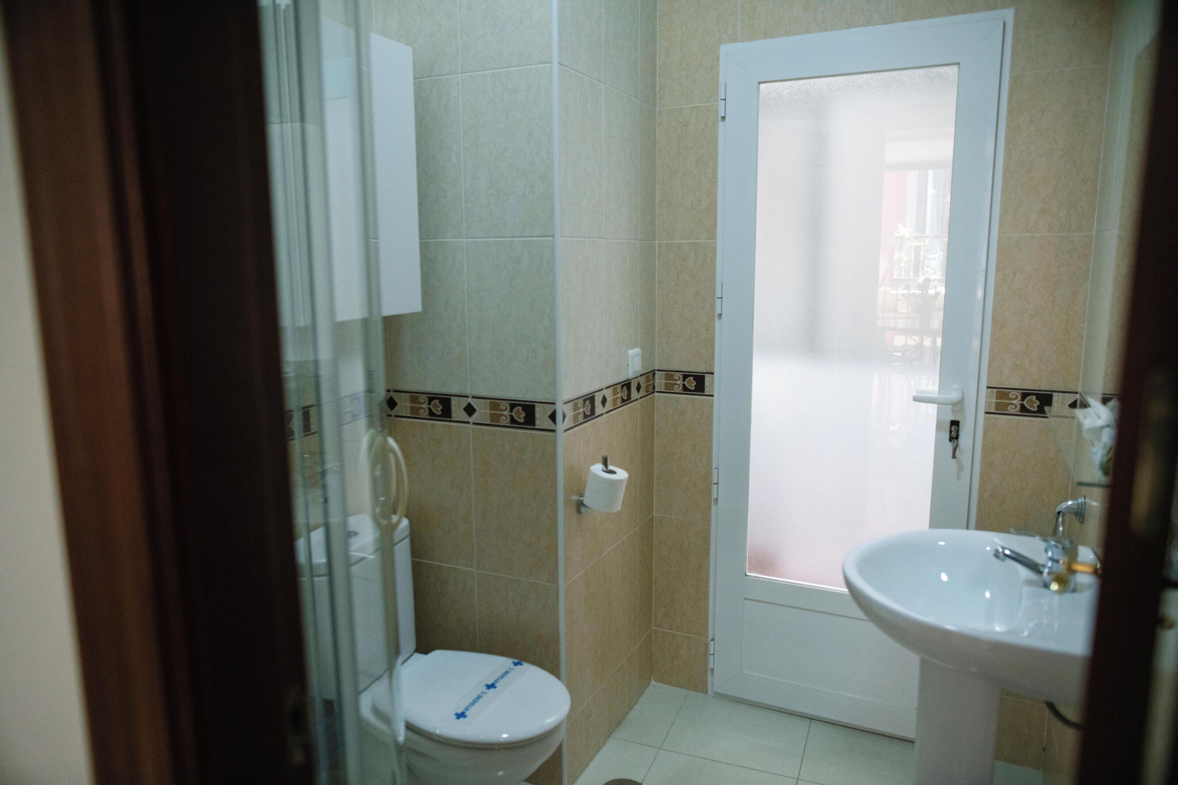 Et badeværelse med toilet, vask og bruseområde.