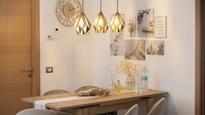 Comedor con mesa de madera, sillas, lámparas colgantes, decoración en la pared y un reloj.