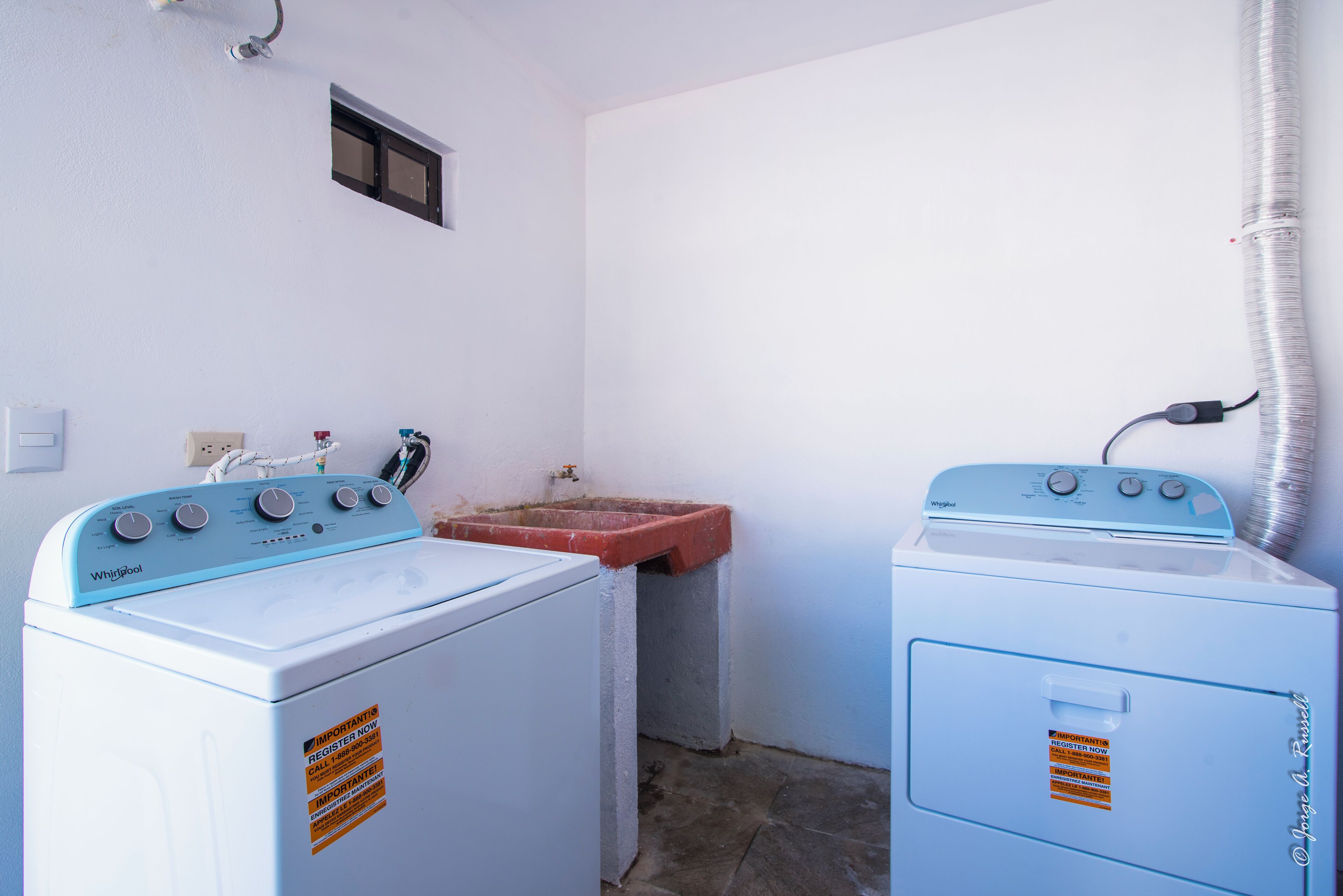 A compact laundry room with two Whirlpool washers and a sink.