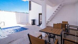 Une terrasse sur le toit avec une piscine, des sièges extérieurs et un escalier menant à un niveau supérieur.