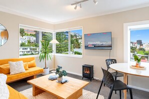 A modern living room with a sofa, coffee table, TV, and a fireplace.