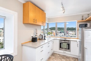 A modern kitchen with a large window, stainless steel appliances, and wooden cabinets.