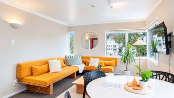 A modern living room with a sofa, a round table, and a TV mounted on the wall.