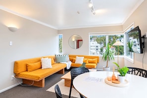 A modern living room with a sofa, a round table, and a TV mounted on the wall.