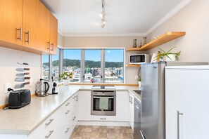 A modern kitchen with a view of a cityscape, stainless steel appliances, and a window with a city view.